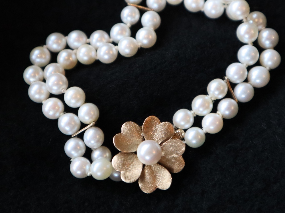 A pearl bracelet, with two rows of regular pearls, to a yellow metal floral shaped clasp,