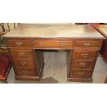 An Edwardian mahogany desk with a rectangular moulded top above a central drawer and two banks of