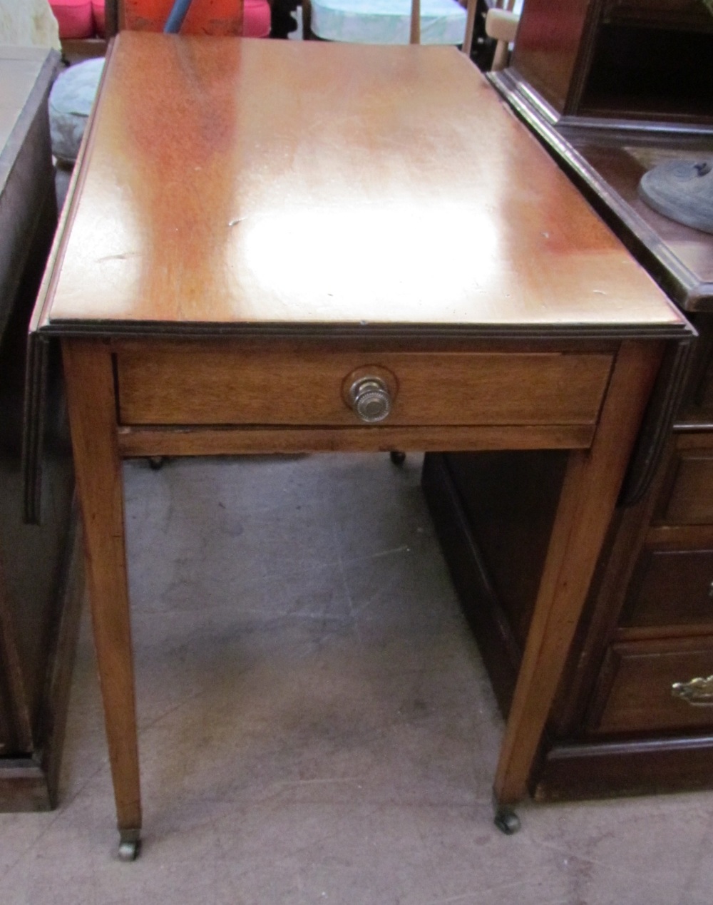 A Victorian mahogany Pembroke table with drop flaps on square tapering legs and casters