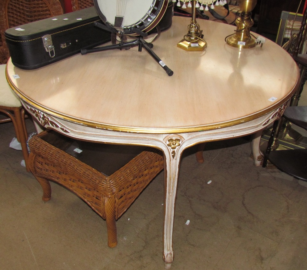 A 20th century dining table of round form with a gilt edge on leaf carved legs