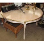 A 20th century dining table of round form with a gilt edge on leaf carved legs