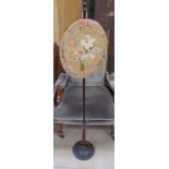 A Victorian pole screen, the oval screen embroidered with flowers, leaves and swags,