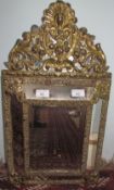 A brass framed wall mirror with a shell and flowers