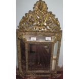 A brass framed wall mirror with a shell and flowers