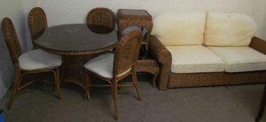 A conservatory suite comprising a glass topped dining table and four chairs together with a settee