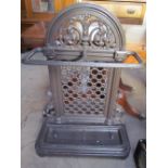 A cast iron umbrella stand with leaf cast decoration and two drip trays