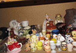 A collection of pottery egg cups together with novelty tea pots, commemorative mugs, jugs,