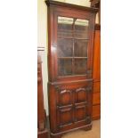A 20th century oak standing corner cupboard with a moulded cornice and a glazed door,