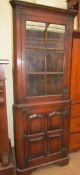 A 20th century oak standing corner cupboard with a moulded cornice and a glazed door,