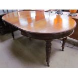 An Edwardian oak extending dining table with two additional leaves on reeded and fluted legs and