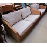 A wicker upholstered three seater settee with matching two seater example