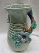 A Clarice Cliff moulded pottery vase decorated with flower heads and leaves to a green ground