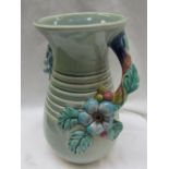 A Clarice Cliff moulded pottery vase decorated with flower heads and leaves to a green ground