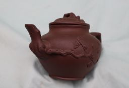 A Yixing pottery teapot, decorated with raised flowers and leaves,