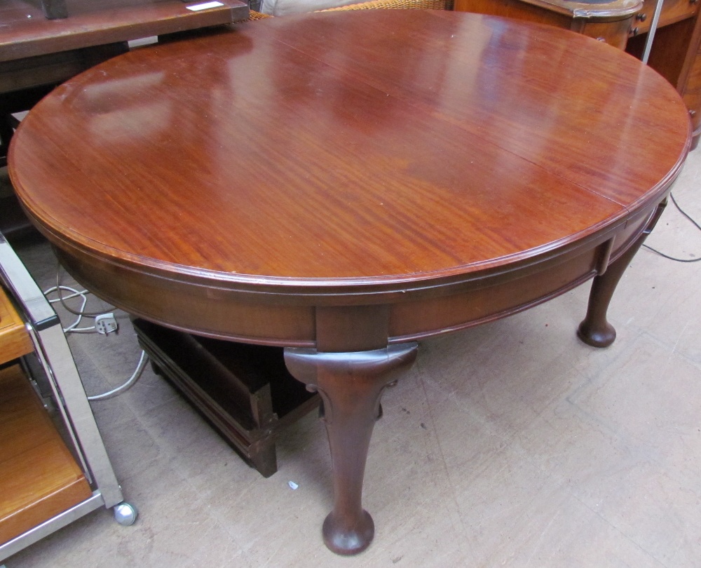 An Edwardian mahogany extending dining table of oval form with cabriole legs and pad feet,