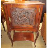 An Edwardian mahogany music cabinet with a leaf carved door on leaf carved cabriole legs united by