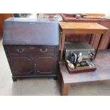 A reproduction mahogany bureau together with a Singer sewing machine in a faux crocodile case and