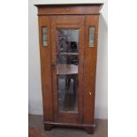 An Edwardian oak wardrobe, the moulded cornice above a mirrored door on bracket feet