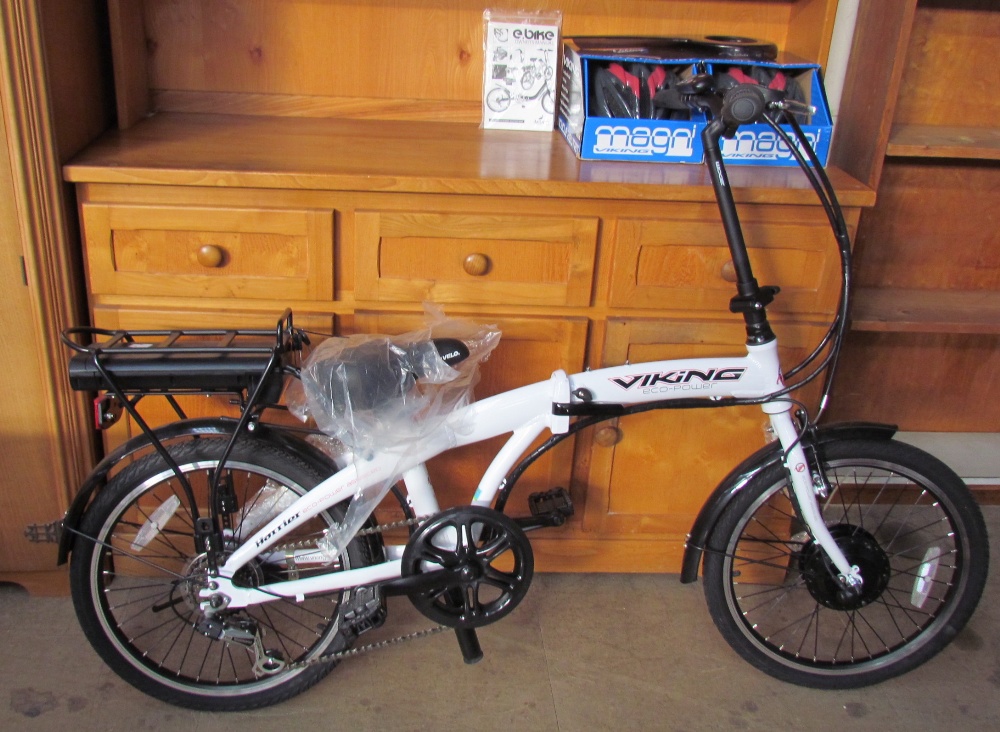 A Harrier Viking Eco-Power folding electric bicycle, in white, together with bicycle helmets