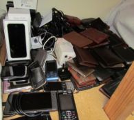 An iPhone SE together with other mobile phones and a collection of leather wallets and card cases