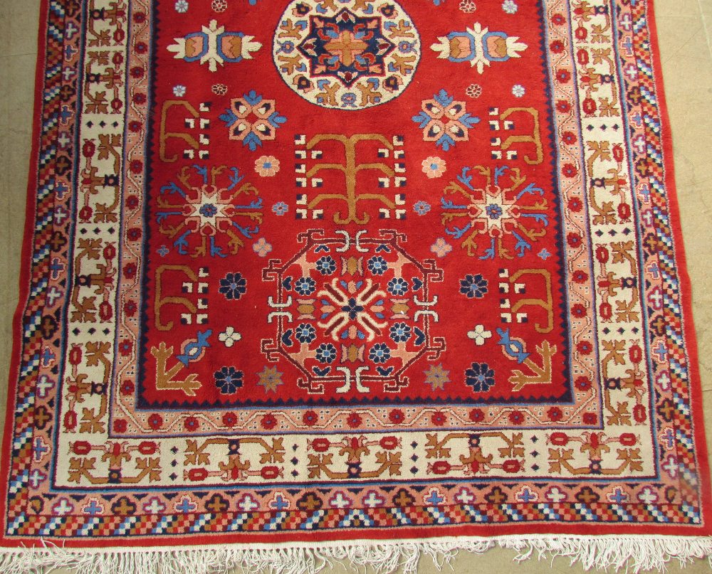 A red ground rug, with a central round medallion and two shaped medallions, with multiple floral - Image 2 of 2