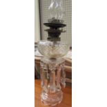 A Victorian cut glass oil lamp with lustre drops on spreading feet