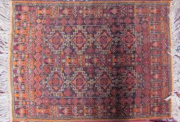 A small orange ground rug decorated with geometric panels and border together with a small pink