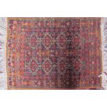 A small orange ground rug decorated with geometric panels and border together with a small pink