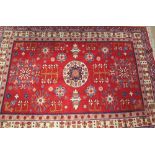 A red ground rug, with a central round medallion and two shaped medallions, with multiple floral