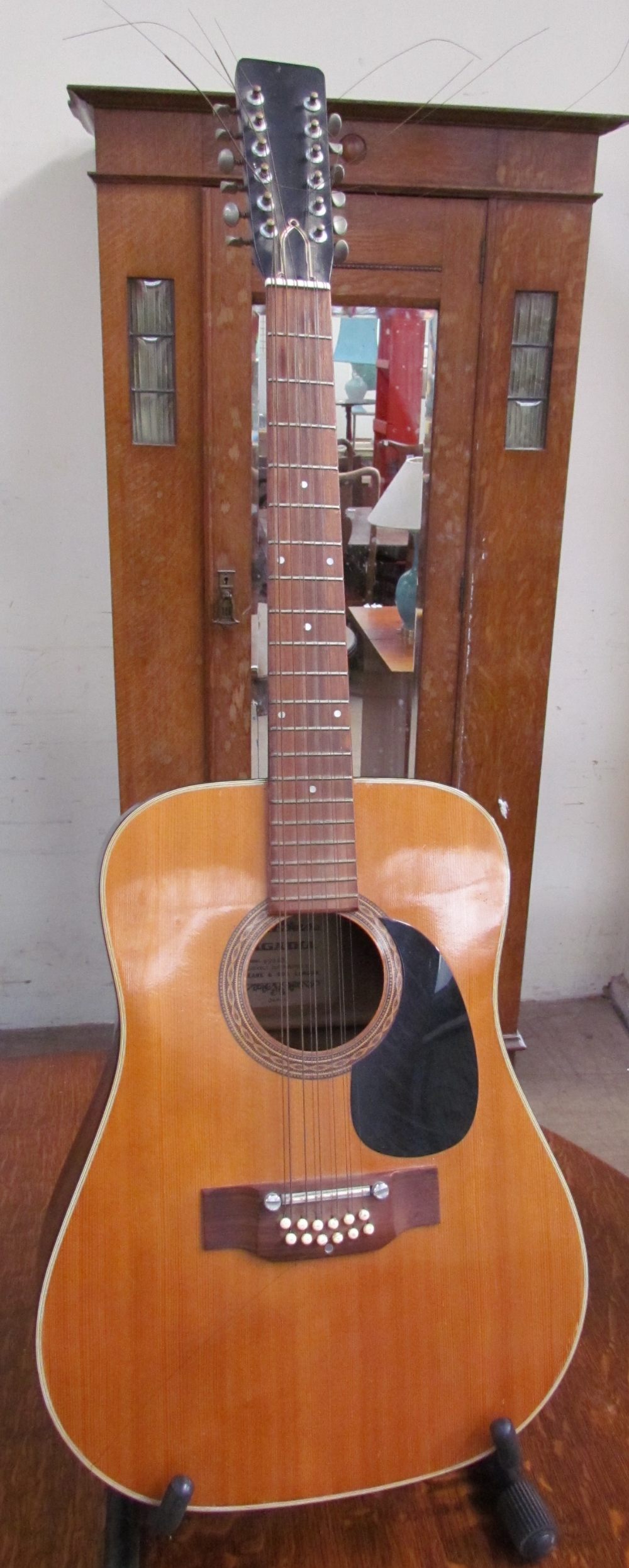 A Sagadia model 9204S twelve string acoustic guitar on a stand