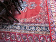 A room size rug with an orange ground, decorated with flowers and leaves to a multiple guard stripes