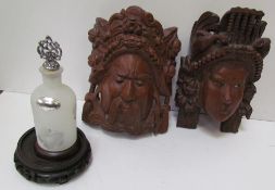 A pair of Balinese carved masks and a glass and white metal bottle