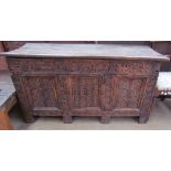 A 17th century carved coffer with a planked top and carved front