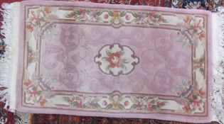 A Chinese pink ground rug with a central rose together with a Kashmir rug and two other rugs