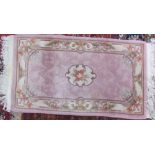 A Chinese pink ground rug with a central rose together with a Kashmir rug and two other rugs