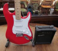 A Rockburn six string electric guitar, in red, together with a G-10 practice amp