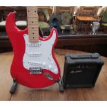 A Rockburn six string electric guitar, in red, together with a G-10 practice amp