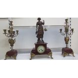 A clock garniture with a fisherwoman surmount, flanked by a pair of candelabra