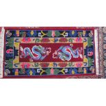 A Chinese rug decorated with dragons to a red ground with radiating guard stripes decorated with