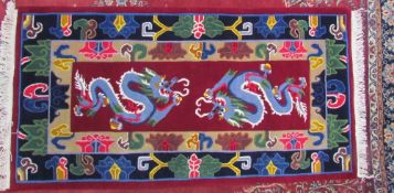 A Chinese rug decorated with dragons to a red ground with radiating guard stripes decorated with