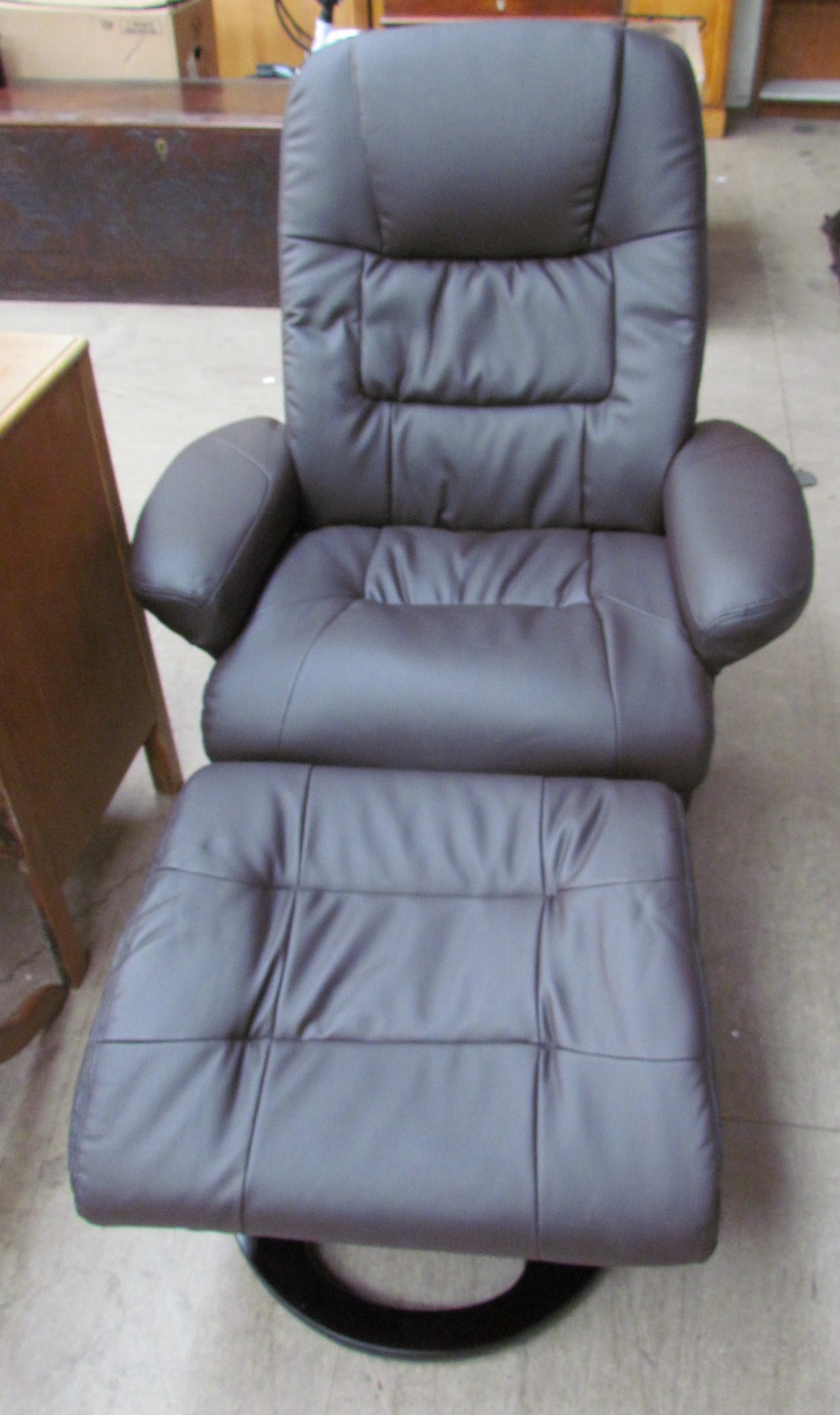 An unused brown leather swivel chair and matching footstool, with massage and heat function on the