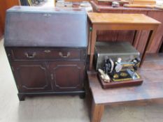 A reproduction mahogany bureau together with a Singer sewing machine in a faux crocodile case and a