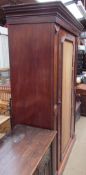 A Victorian mahogany wardrobe with a moulded cornice above a single door on a plinth base