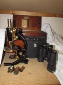 A black lacquer and brass monocular microscope with additional lenses and box together with a pair