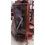 An Edwardian mahogany corner cupboard with a single glazed door on square legs,