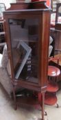 An Edwardian mahogany corner cupboard with a single glazed door on square legs,