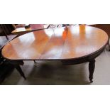 An Edwardian oak extending dining table with two additional leaves on reeded and fluted legs and