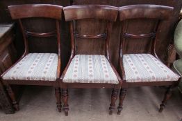 A set of three Regency mahogany dining chairs with an outswept top rail with a bar back and drop in