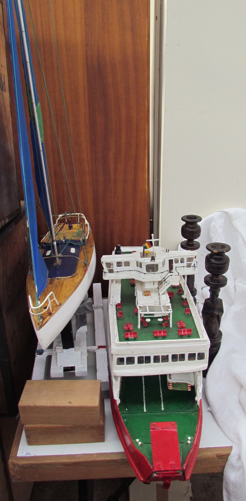 A model of a Red Funnel ferry together with a model yacht and a pair of carved African candlesticks