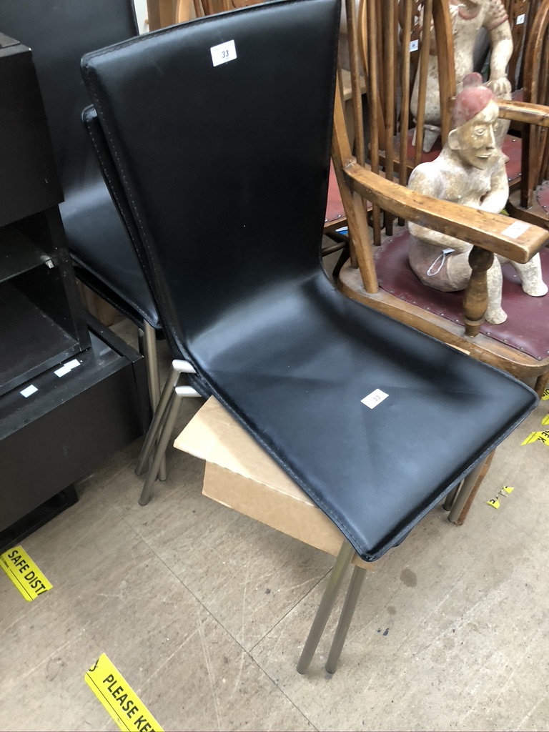 A set of four black leatherette dining chairs on chrome legs